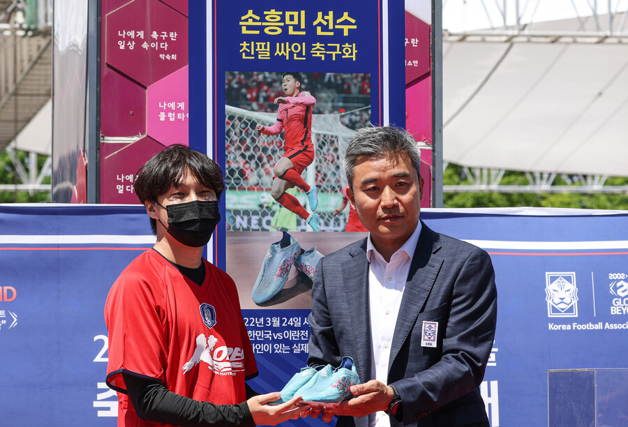 ▲ 손흥민이 이란전에서 신고 뛰었던 축구화 낙찰에 성공한 이재호(왼쪽) 씨가 대한축구협회 관계자로부터 축구화를 건네 받고 있다. ⓒ연합뉴스