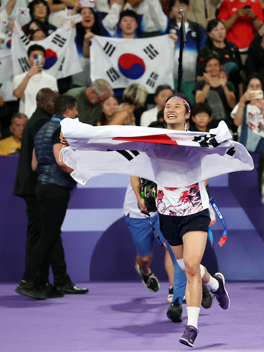▲ 5일(현지시간) 프랑스 파리 포르트드 라 샤펠 아레나에서 열린 2024 파리올림픽 배드민턴 여자 단식 결승전에서 중국 허빙자오를 이기고 우승을 차지한 한국 안세영이 태극기를 들고 경기장을 뛰고 있다. ⓒ연합뉴스