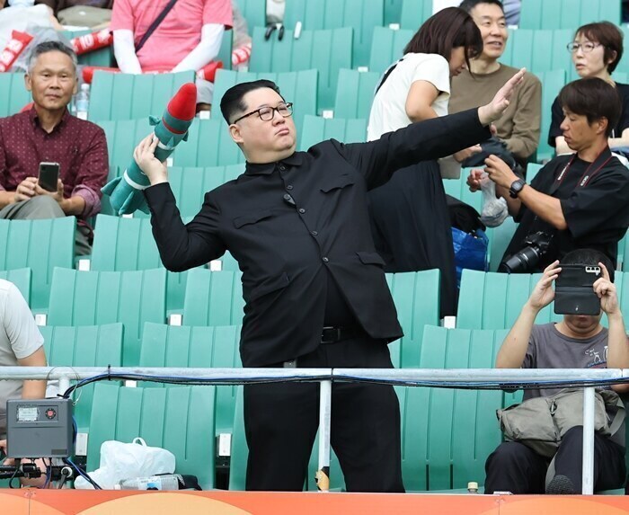 ▲ 21일 일본 시즈오카현 후쿠로이의 시즈오카 스타디움 에코파에서 열린 2026 아이치·나고야 아시안게임 여자 축구 조별리그 대한민국과 북한의 경기. 관중석에 북한 김정은 국무위원장을 흉내낸 듯한 관람객이 눈길을 끌고 있다. ⓒ연합뉴스